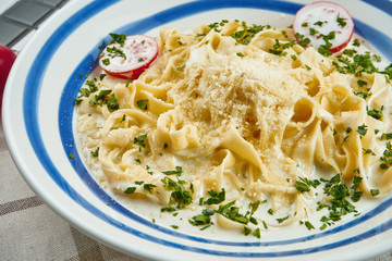 Italian fettuccine pasta in cheese sauce with parmesan, cherry tomatoes and herbs in white ceramic bowl on white background. Tasty food background