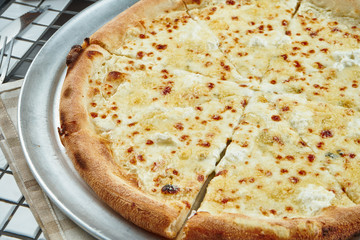 Close up view on tasty homemade italian four cheeses pizza in a composition with spices and cherry tomatoes on a white background. Top view. Food flat lay
