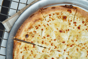 Close up view on tasty homemade italian four cheeses pizza in a composition with spices and cherry tomatoes on a white background. Top view. Food flat lay