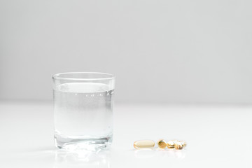 Medical mood - glass of drinking water and pills (tablets or drugs).