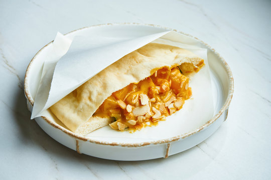 Tasty Street Food - Pita With With Shrimp And Peanut Sauce In Parchment On A White Ceramic Plate On A Marble Background.. Greek Cuisine. Close Up