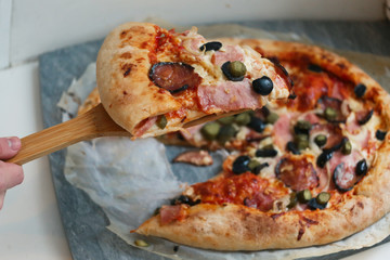 slice of pizza with hum, sausage,cucumber, olives onion and cheese crust close up photo