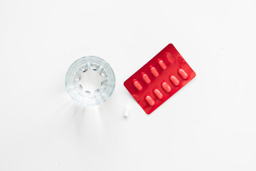 Medical mood - glass of drinking water and pills (tablets or drugs).