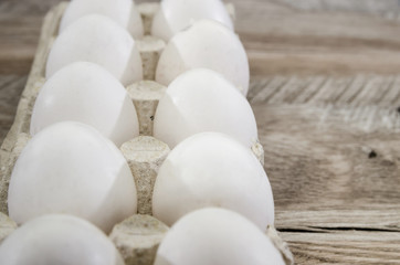 white chicken eggs in a tray on a wooden table.