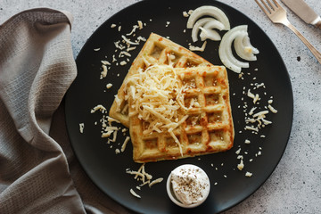 Tasty waffles with zucchini and cheese. Waffles served with cheese, onions, sour cream and spices. Waffles on a plate