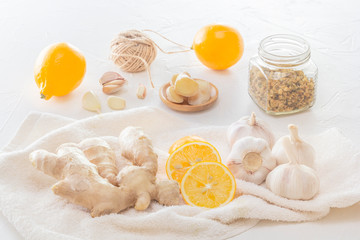 Ginger, garlic, lemon and a dry medical chamomile in a jar - a means to protect against viral infections and colds on a light wooden table.