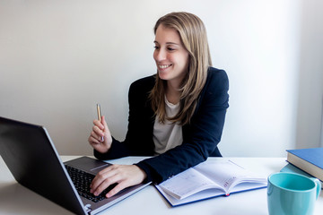 Smiling young female entrepreneur sitting at home working with her laptop