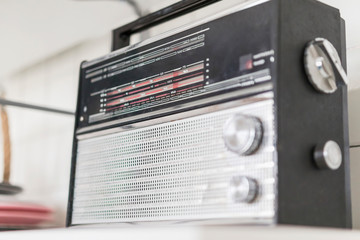 an old Soviet radio receiver from Russia in black with a silver grille on a white shelf