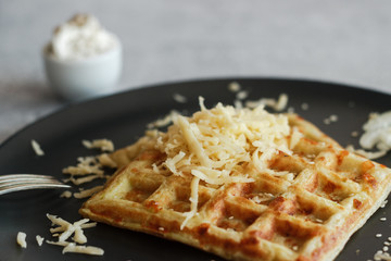 Tasty waffles with zucchini and cheese. Waffles served with cheese, onions, sour cream and spices. Waffles on a plate