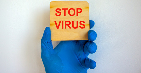 COVID-19 Pandemic Coronavirus concept.The doctor holds in his hand a tablet saying stop virus. Gloved hand.