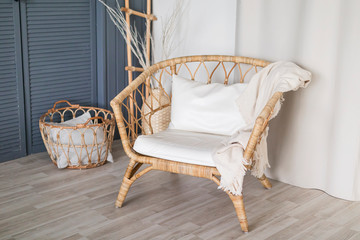 wicker wooden chair with white pillows and a blanket