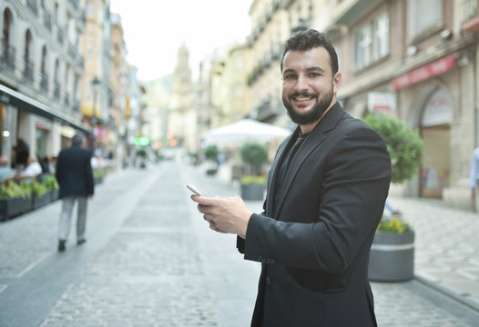 Bearded man looking phone in city outdoors