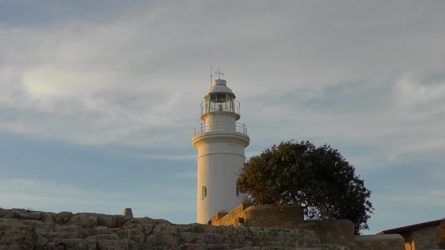 The old lighthouse rises above the wall of the ancient amphitheater. Filmed on the territory of the park Royal Tombs, near Paphos, Cyprus. 