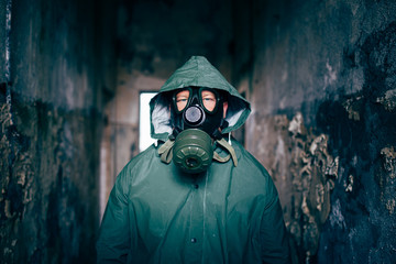 Dramatic portrait of a man wearing a gas mask in a ruined building.