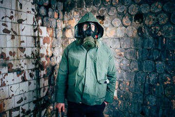 Dramatic portrait of a man wearing a gas mask in a ruined building.