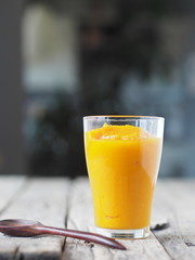 A glass of natural smoothie, juice, cocktail made at home from the pulp of homemade pumpkin, on a blurred kitchen background.Health benefits of pumpkin.