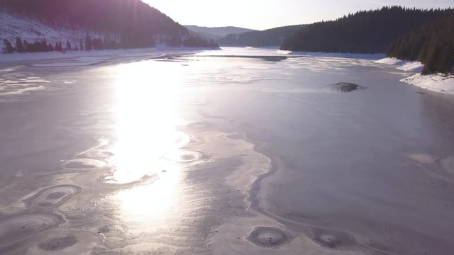 Bright Sunlight Reflection On Frozen Lake Neath The Mountains In Transylvania - Wide Shot
