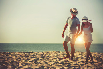 Romantic couple walking holding hands enjoying sunset at the beach