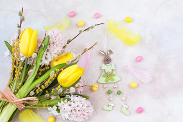 Bouquet of yellow tulips and pink hyacinths, willow and mimosa, rabbit, eggs and feathers