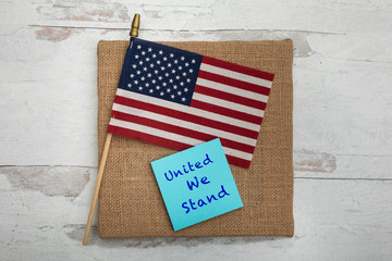 United we stand sign on a blue posted note with an American flag 