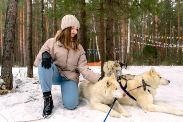 The girl sits next to a white Siberian husky and strokes her. © Alexander