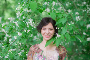 Closeup portrait of attractive woman in spring garden. Beautiful girl in spring landscape background. Springtime. Cover face healthy skin. Beauty clinic skincare organic natural spring