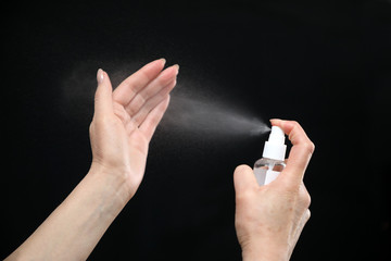 disinfection of the hands .  the disinfectant is sprayed on the hands, protecting against viruses and bacteria. on a black background . copy space.