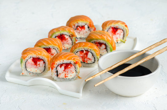 Salmon sushi set on a white plate. Sushi roll with red fish, salmon, red caviar. Roll with fresh salmon, soft avocado, with shrimp and crab and cream cheese under a wide layer of massago caviar.