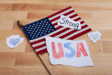 Obraz premium America flag laying on a wooden table strong USA written on pieces of paper with blue heart 