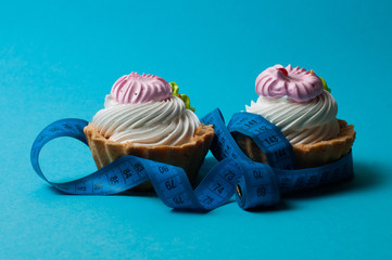 Two cakes and centimeter on a blue background. Holiday concept, weight control and healthy eating.