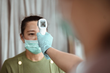 Doctor check patient body temperature using infrared forehead thermometer at hospital for Corona...