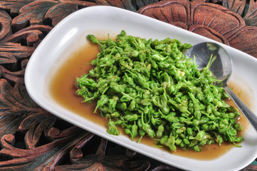 Stir fried cowslaw in oyster sauce on a white plate on a wooden table