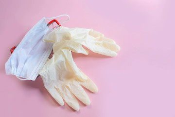 Supermarket basket with gloves and a medical mask on a pink background. Concept of coronavirus and air pollution.