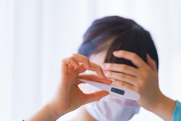 Japanese woman measures fever with thermometer