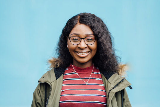 Portrait Og Young Nigerian Woman Student Wearing In Khaki Coat In Eyeglasses On Blue