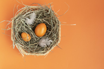 Orange eggs in the wicker basket on the orange background. Copy space. Place for text and design. Happy Easter. Top view. Flat layout.