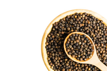 Many black pepper seeds in a wooden cup. Top view and isolated. copy space.