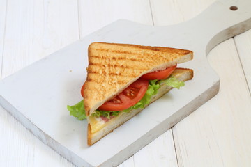 Sandwich with tomatoes, cheese and ham on a white background