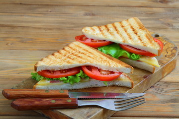 Sandwich with tomatoes, cheese and ham on a dark, wooden background