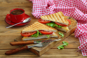 Sandwich with tomatoes, cheese and ham on a dark, wooden background