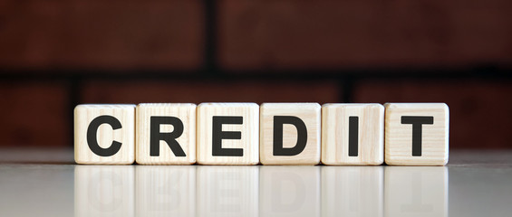 Obraz premium CREDIT - business financial concept on on a dark brick background. Wooden cubes with text