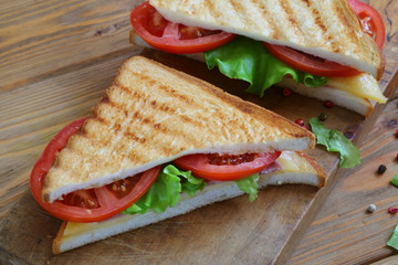 Sandwich with tomatoes, cheese and ham on a dark, wooden background
