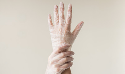 Hands wearing transparent vinyl gloves touching on bright background