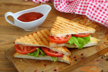 Sandwich with tomatoes, cheese and ham on a dark, wooden background