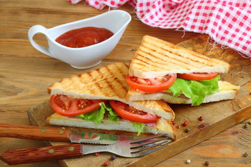 Sandwich with tomatoes, cheese and ham on a dark, wooden background