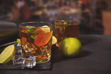 Fresh cocktail Cuba Libre with brown rum, cola, mint and lime on black background. Long Island Iced Tea cocktail.