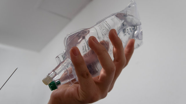manos de enfermera sostienen suero y aguja