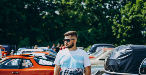 Handsome man in sunglasses near retro cars.