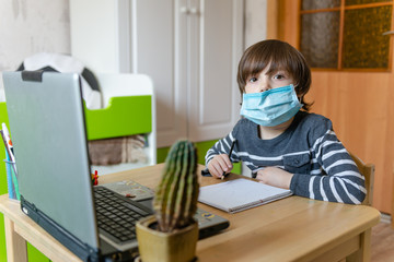 Distance learning for children during the coronavirus epidemic. A boy sits at a table and performs...