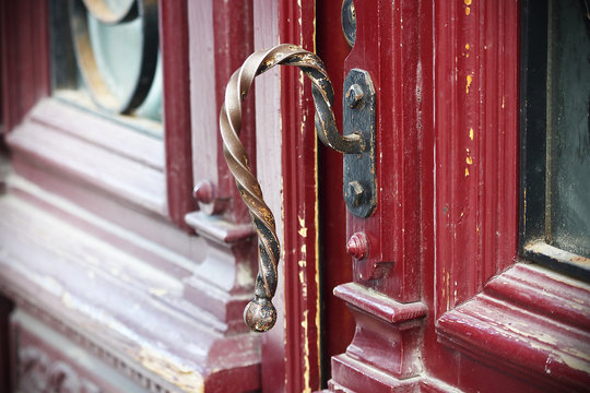 Gilded iron croocked door handle on red painted wooden door